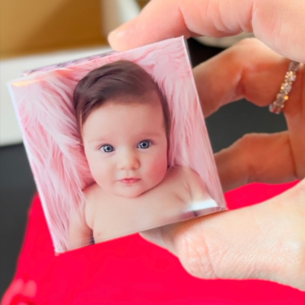 Hand holding a 2x2 square custom photo magnet with baby portrait